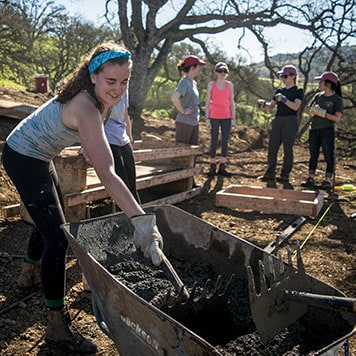 Alternative Spring break participant using tools on a trail project