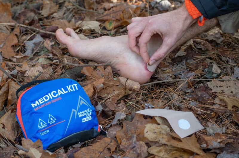 Hiker treats a blister on a fall hike.