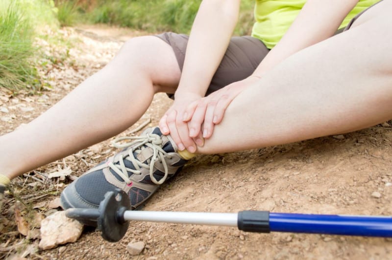 Hiker with a sprained ankle sits along a trail.