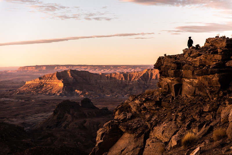 Hiker over looks desert canyon at sunrise