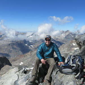 Mike DiFabio sits on a high alpine peak with a big smile