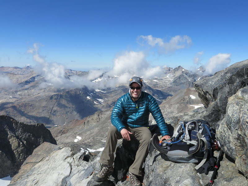 Mike DiFabio sits on a high alpine peak with a big smile