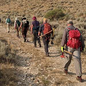 Volunteers hold tools and walk along a trail in Cody, Wyoming