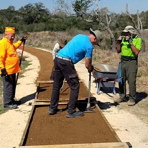 Trail volunteers with tools work on smoothing out a newly built accessible trail located outside the Aransas Wildlife Refuge Visitor Center in Aransas, Texas.