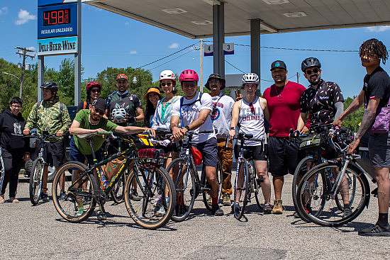 Group photo of everyone with their bikes in front of a gas station