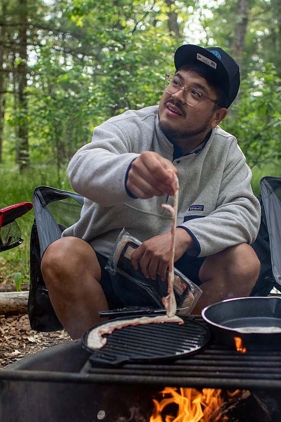 A participant cooks beacon on an open fire