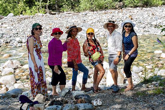 Group of participants pose in a line at the edge of a rocky river