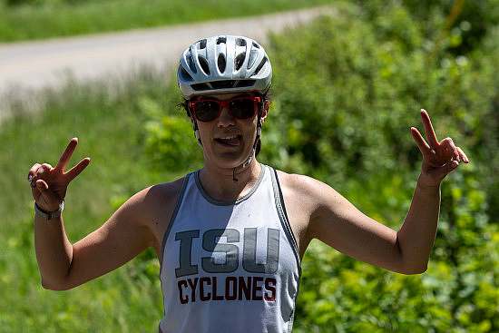 A person in a bike helmet holds up two fingers in a peace sign on both hands
