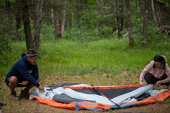 two participants work to set up a tent