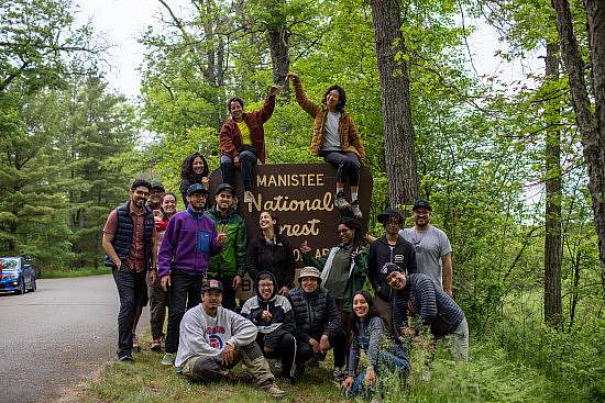 Trip participants take a group photo infront of the Huron-Manistee National Forest sign