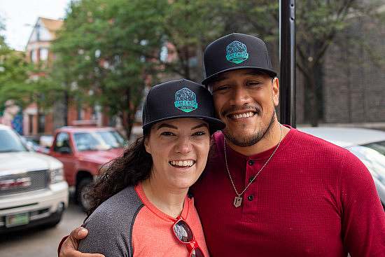 Two trip participants pose for a photo wearing their "Leave it Better" black trucker hats