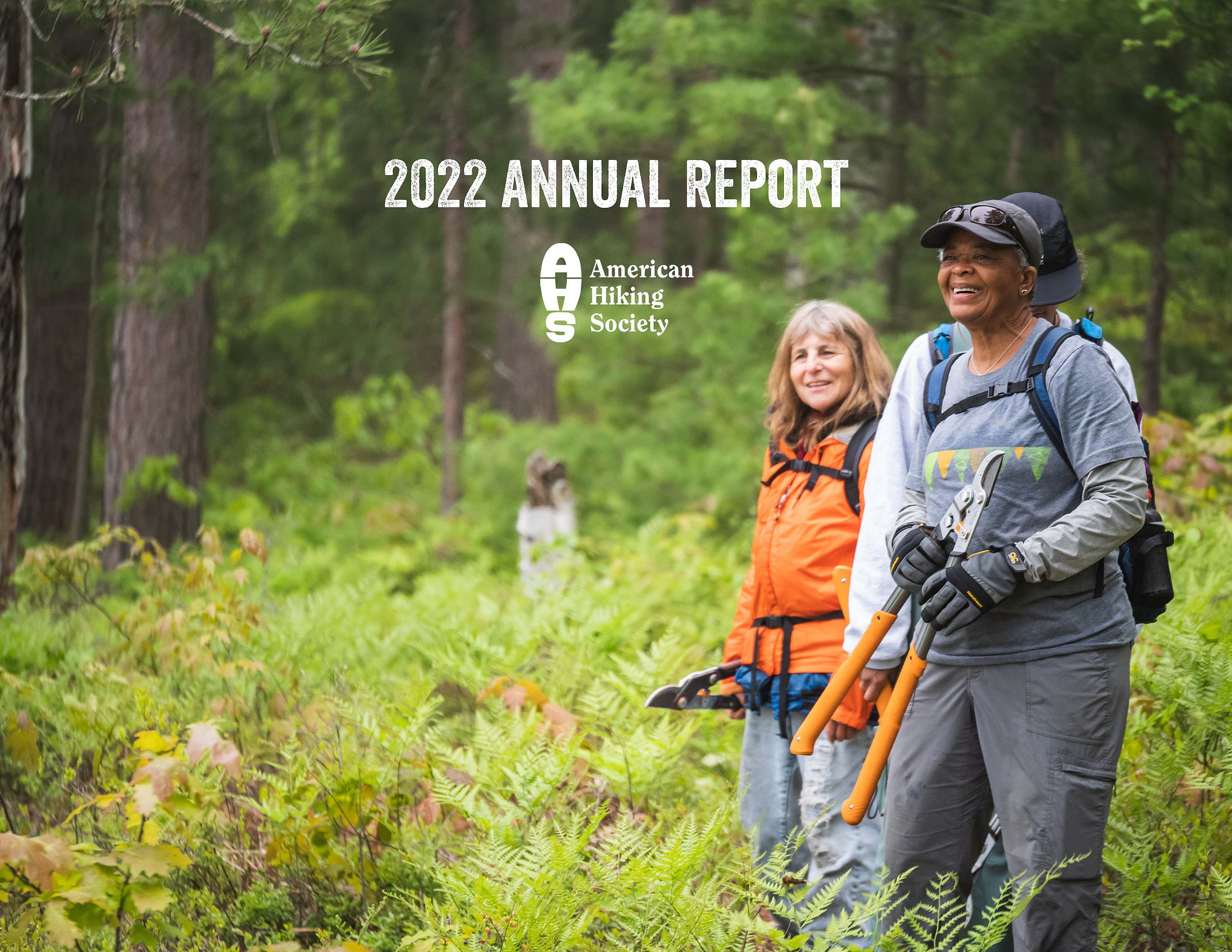 Cover of the 2022 American Hiking Society Annual report. Two volunteers smile while holding loppers in a lush forest with ferns and evergreens