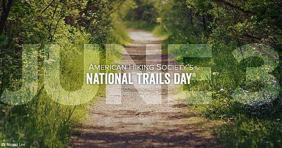 American Hiking Society's National Trails Day June 3 wordmark overlay on a gravel trail close up lined with green vegetation along the edges of the trail.