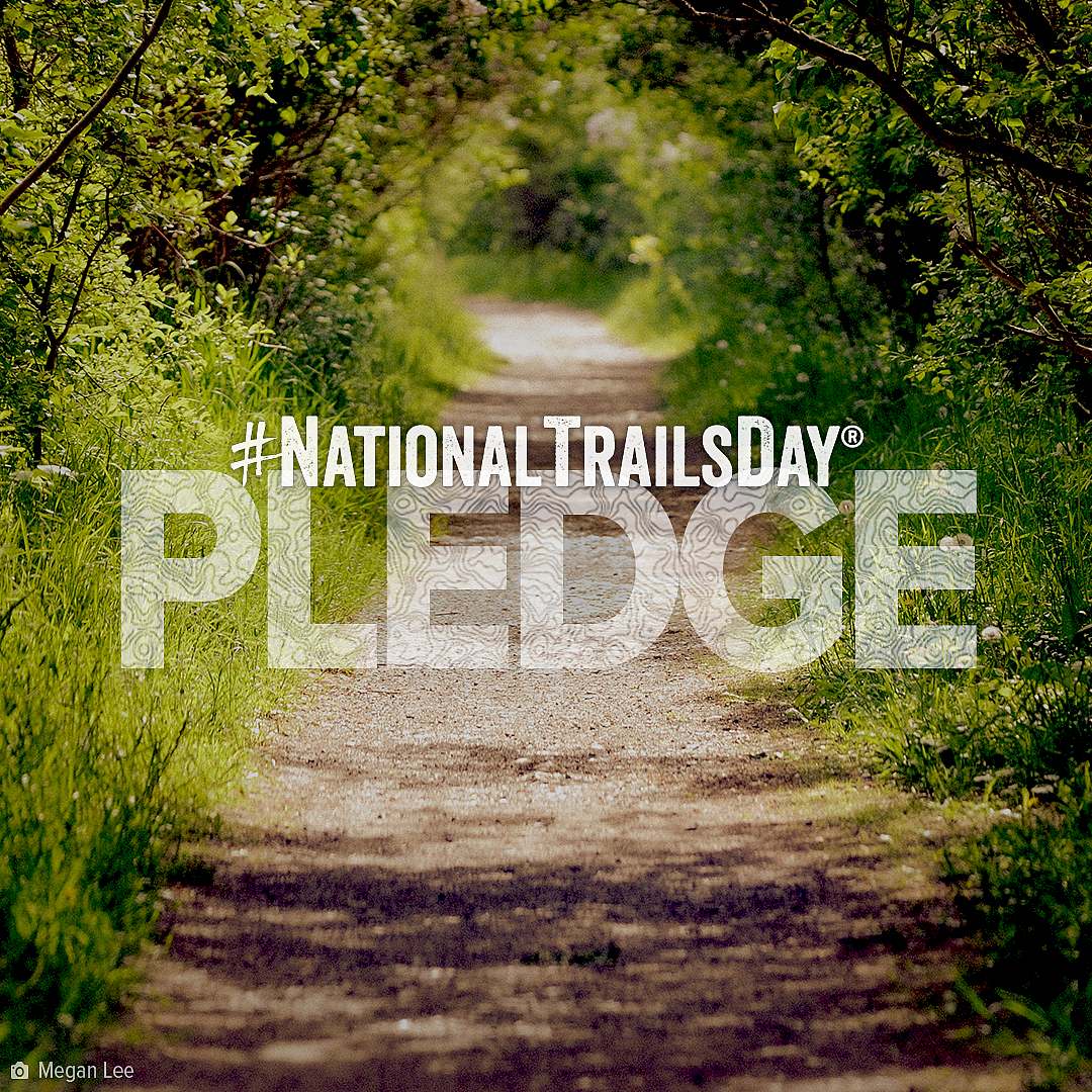 American Hiking Society's National Trails Day Pledge wordmark overlay on a gravel trail close up lined with green vegetation along the edges of the trail.