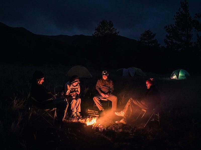 Four volunteers enjoy the evening around a campfire.