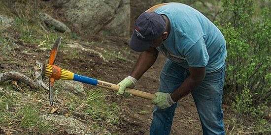 Get invloved - Man swings pick mattock while maintaing a trail